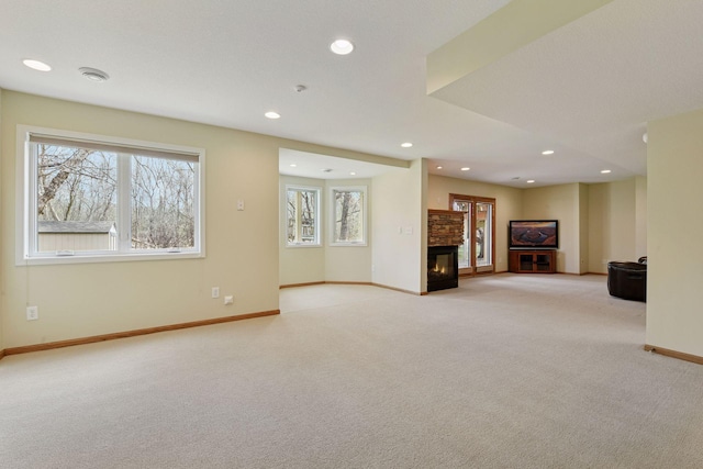 basement featuring light colored carpet, a glass covered fireplace, recessed lighting, and baseboards