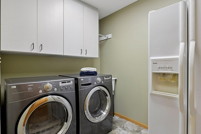 clothes washing area featuring washer and dryer, cabinet space, and baseboards