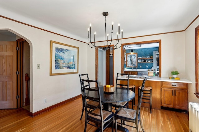 dining room featuring radiator heating unit, arched walkways, light wood-type flooring, baseboards, and an inviting chandelier