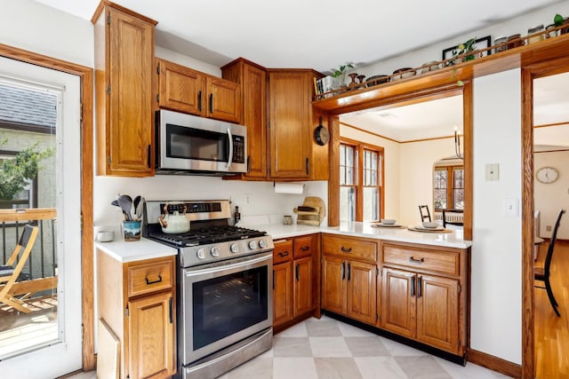 kitchen featuring light countertops, light floors, brown cabinetry, and stainless steel appliances