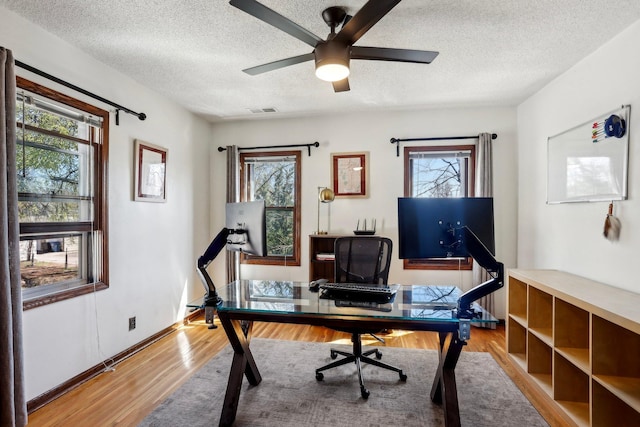 office space with ceiling fan, a textured ceiling, visible vents, and wood finished floors