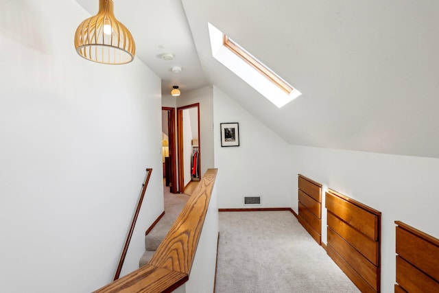 additional living space with vaulted ceiling with skylight, baseboards, light carpet, and visible vents