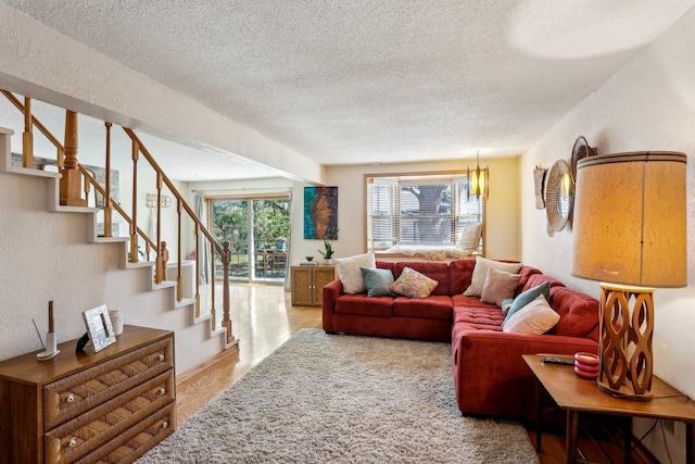 living area with stairs, a textured ceiling, a textured wall, and wood finished floors