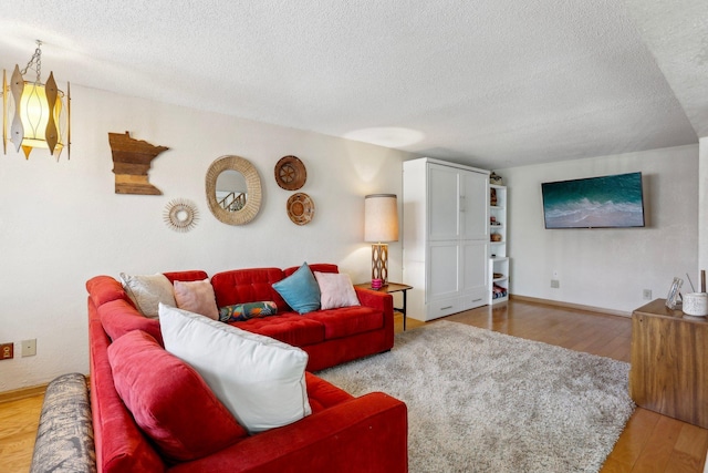 living area featuring baseboards, a textured ceiling, and wood finished floors