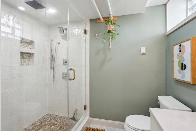bathroom with vanity, toilet, baseboards, visible vents, and a stall shower