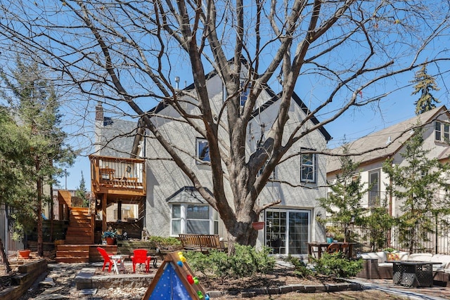 back of house featuring a chimney, a deck, fence, an outdoor hangout area, and a patio