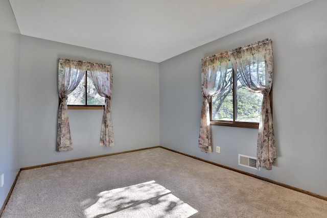 unfurnished room with baseboards, visible vents, and carpet