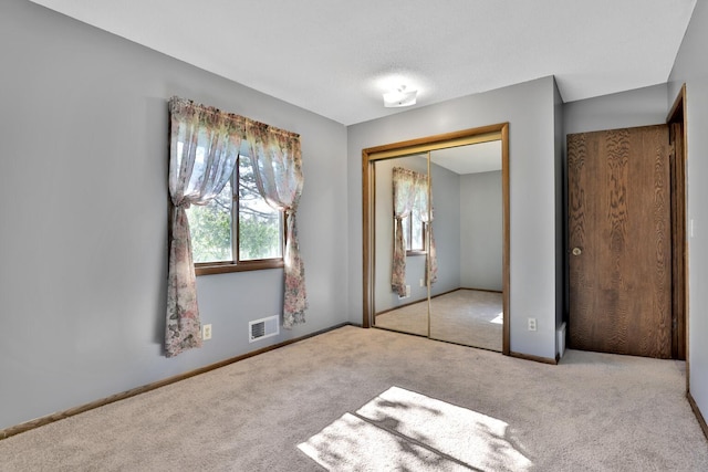 unfurnished bedroom featuring carpet flooring, a closet, baseboards, and visible vents