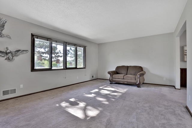 unfurnished room featuring a textured ceiling, carpet floors, baseboards, and visible vents