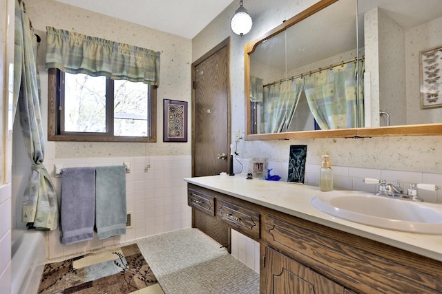 bathroom featuring tile walls, curtained shower, vanity, and a wainscoted wall