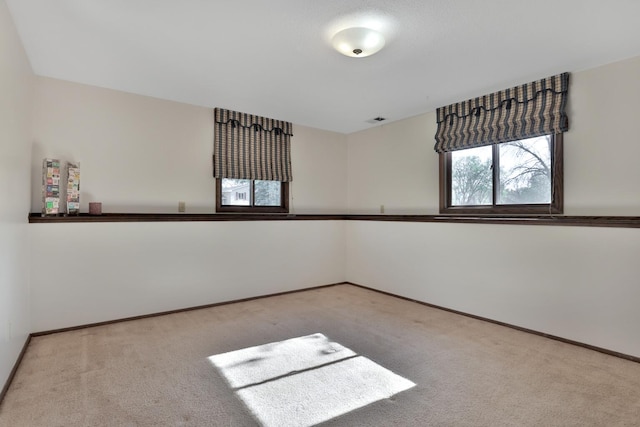 carpeted spare room featuring baseboards and visible vents