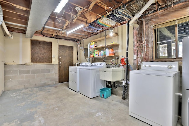 clothes washing area with washer and dryer, laundry area, concrete block wall, and a sink