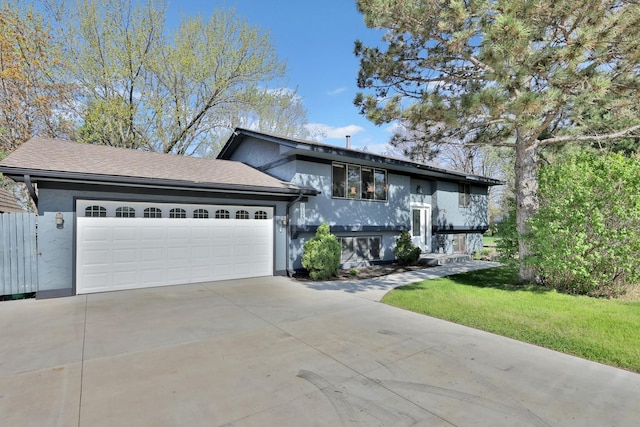 bi-level home with a front yard, stucco siding, driveway, and a garage