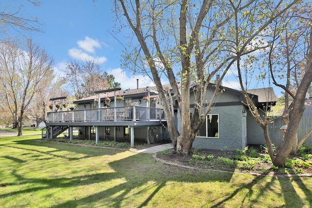 back of property with a yard, a wooden deck, stucco siding, and stairway