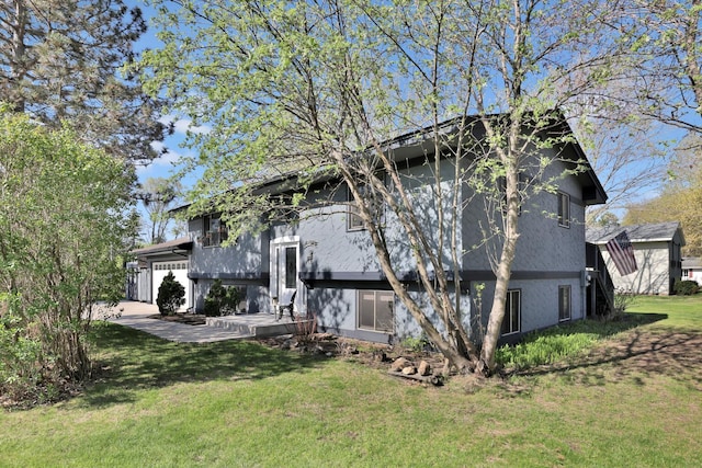 rear view of house featuring a yard and stucco siding