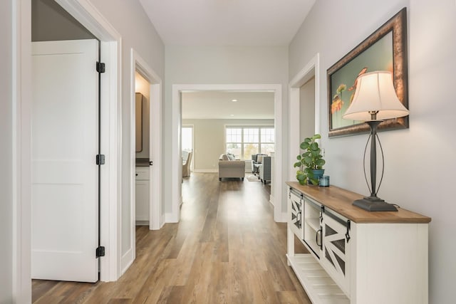 corridor featuring baseboards and light wood finished floors