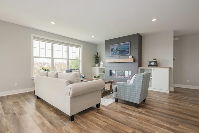 living area featuring baseboards, a large fireplace, recessed lighting, and wood finished floors
