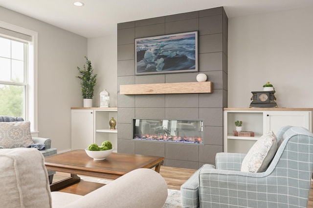 living room featuring recessed lighting, wood finished floors, and a tiled fireplace
