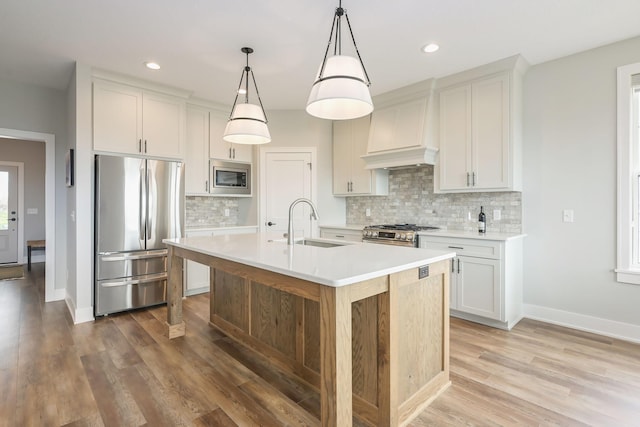 kitchen featuring premium range hood, light countertops, tasteful backsplash, a sink, and appliances with stainless steel finishes