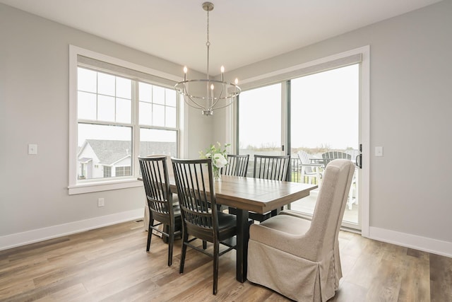 dining area featuring light wood-style floors, baseboards, plenty of natural light, and a chandelier