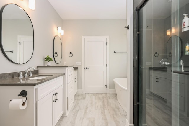 full bathroom with a soaking tub, two vanities, a sink, and a stall shower