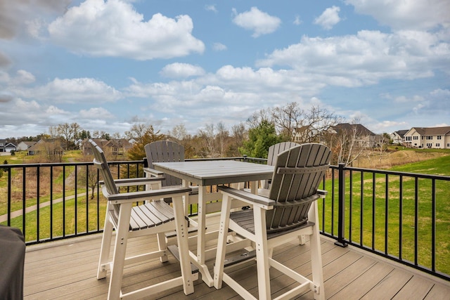 wooden terrace with outdoor dining area, a yard, and a residential view