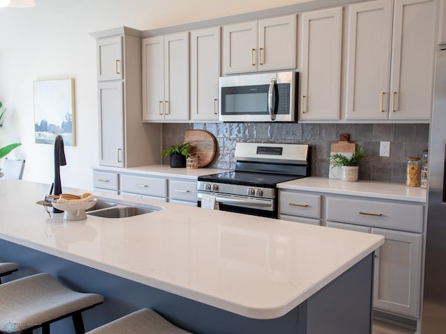 kitchen with backsplash, stainless steel appliances, a sink, and a kitchen bar