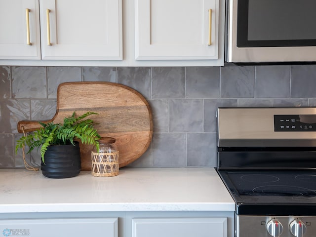 details with backsplash, stainless steel appliances, and white cabinetry
