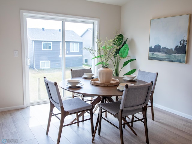 dining space with baseboards and light wood-style flooring