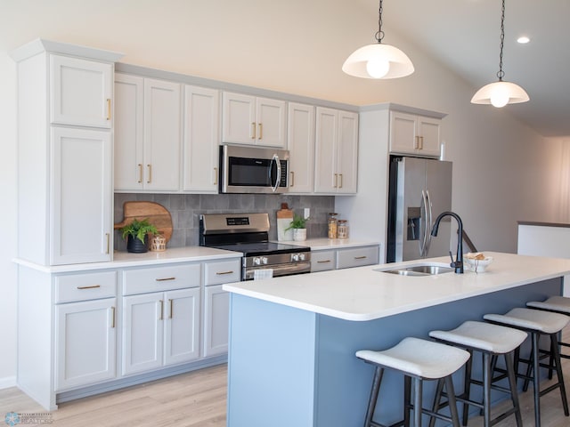 kitchen with decorative backsplash, a breakfast bar, light wood-type flooring, a sink, and stainless steel appliances