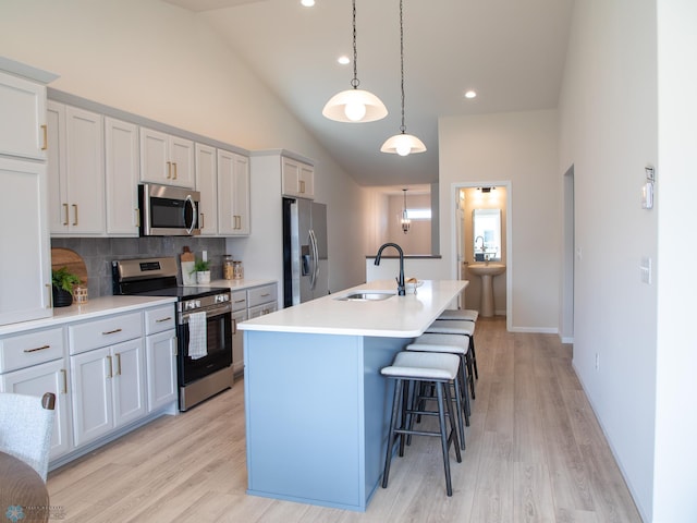 kitchen featuring a sink, backsplash, stainless steel appliances, and light wood finished floors