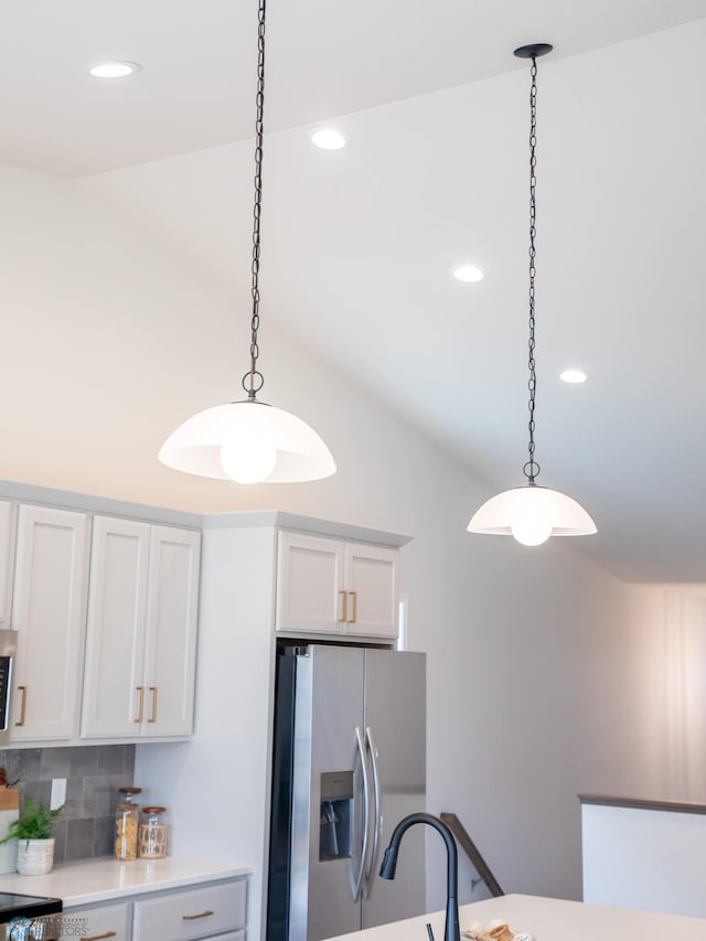 kitchen featuring vaulted ceiling, hanging light fixtures, stainless steel appliances, and tasteful backsplash