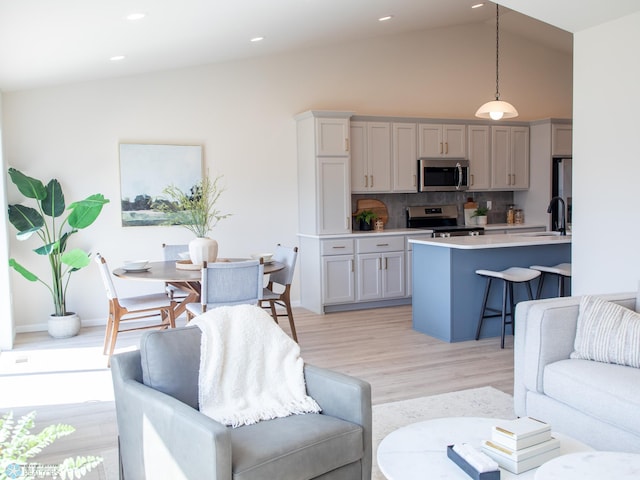 living room with light wood-style floors, high vaulted ceiling, and recessed lighting