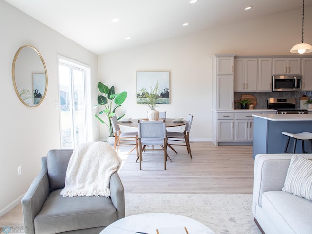 living room with recessed lighting, light wood-style flooring, baseboards, and vaulted ceiling