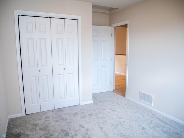unfurnished bedroom featuring carpet floors, baseboards, a closet, and visible vents