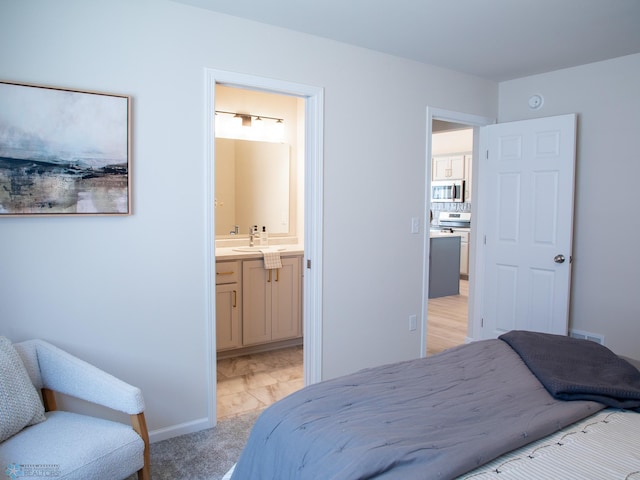 bedroom featuring visible vents, a sink, baseboards, and ensuite bath