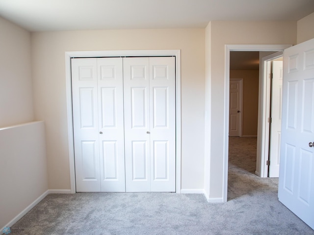 unfurnished bedroom featuring carpet floors, baseboards, and a closet