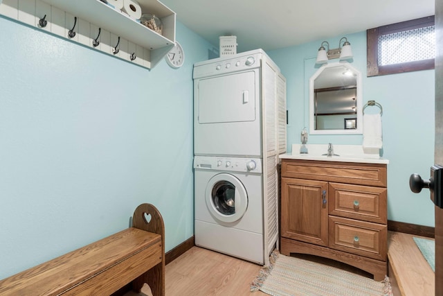 39315 Little Mo Rd, Clitherall Twp, MN 56524 - laundry room with cabinet space, a sink, light wood-style floors, stacked washing maching and dryer, and baseboards