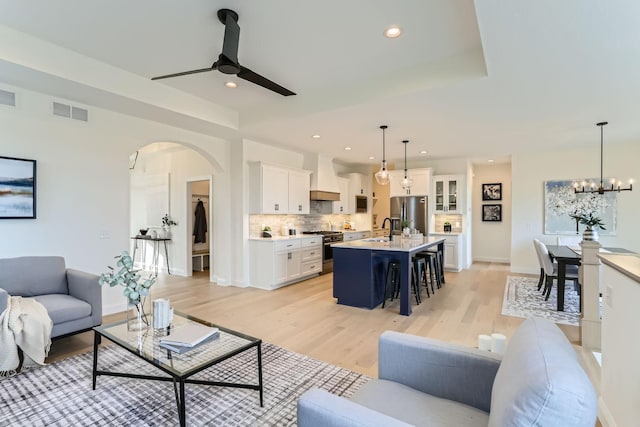 4501 Overlook Dr, Bloomington, MN 55437 - living room with visible vents, arched walkways, light wood-style flooring, and ceiling fan with notable chandelier
