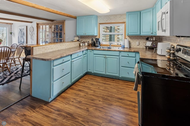 kitchen featuring a peninsula, stainless steel range with electric cooktop, white microwave, and blue cabinets