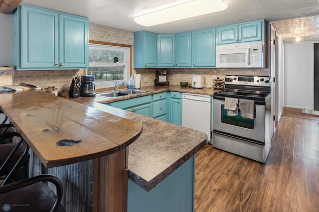 kitchen with dark wood-style floors, blue cabinets, a sink, white appliances, and a peninsula