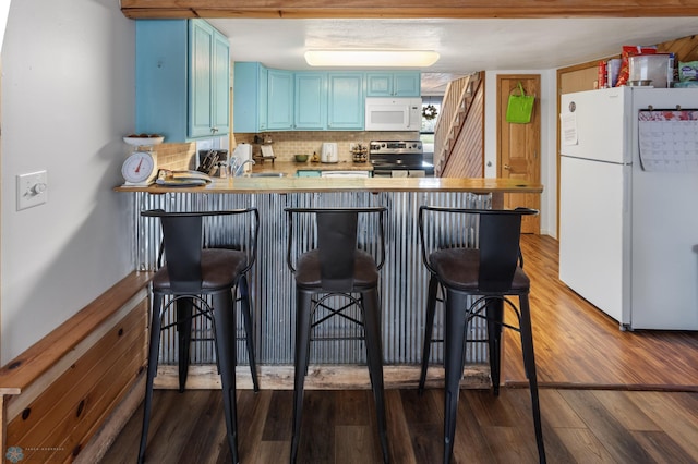 kitchen featuring blue cabinets, a peninsula, backsplash, wood finished floors, and white appliances