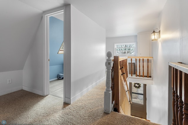 hallway with lofted ceiling, carpet flooring, baseboards, and an upstairs landing