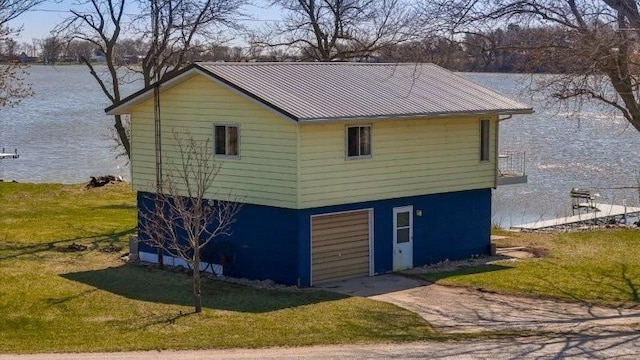 exterior space featuring driveway, metal roof, and a front lawn