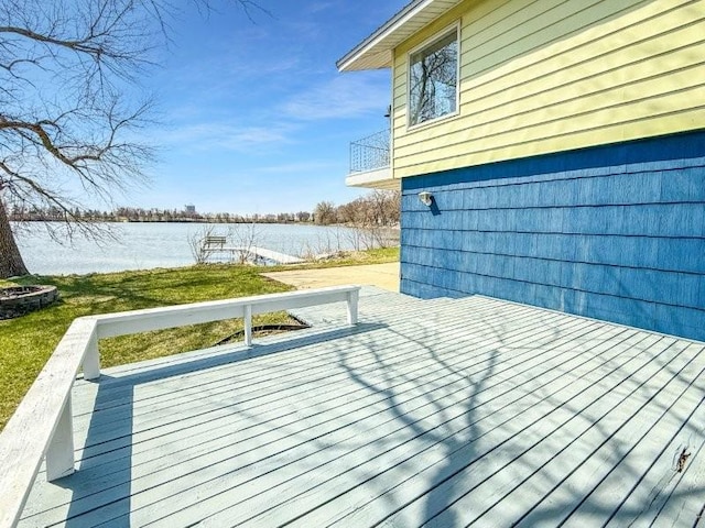 wooden deck with a water view and a lawn