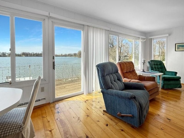 sunroom with a baseboard heating unit and a water view