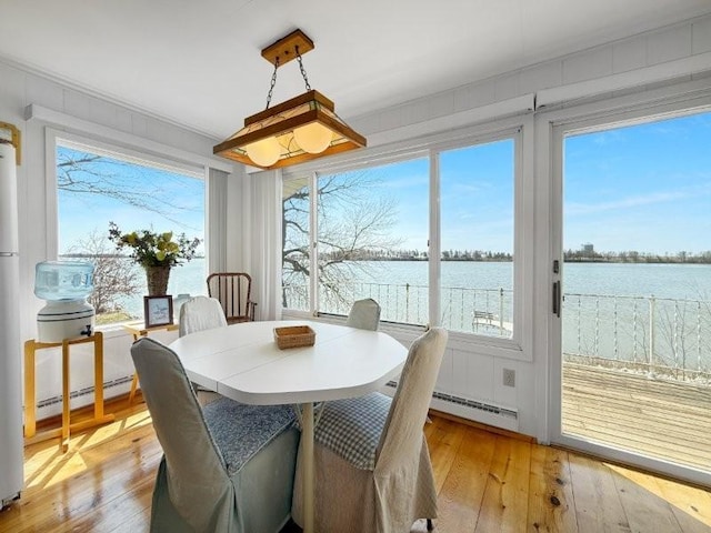 dining space with light wood-style floors, a water view, and baseboard heating