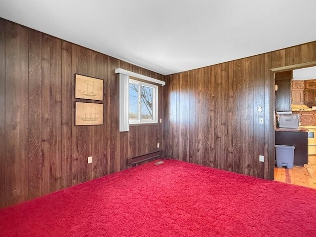 spare room with baseboard heating, wood walls, and wood finished floors