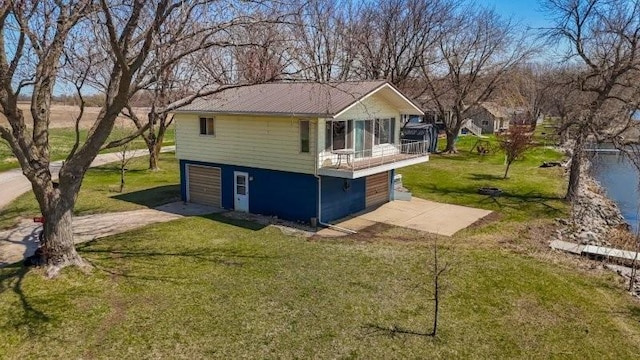 back of property with a garage, concrete driveway, and a lawn