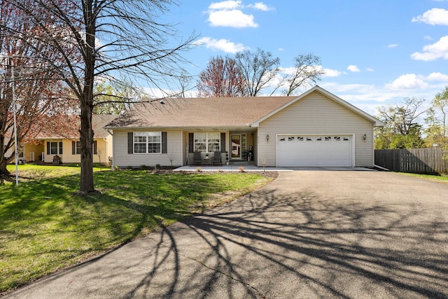 ranch-style home featuring a garage, fence, a front lawn, and aphalt driveway